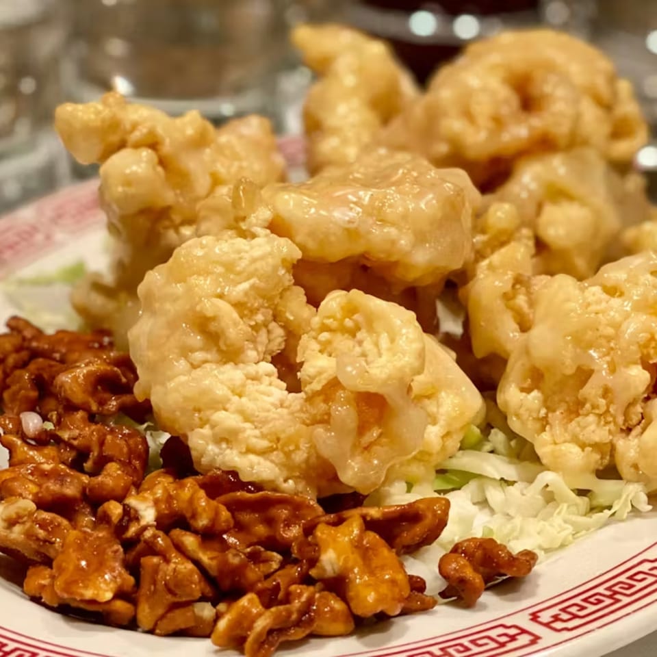 Crispy honey walnut shrimp and candied walnuts on a bed of lettuce, served on a white plate.