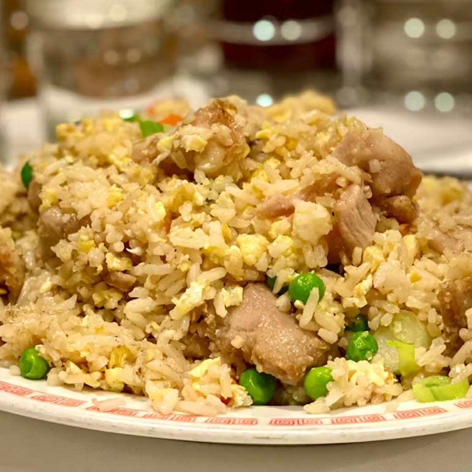 A close-up of Lai Lai Restaurant's chicken fried rice with peas and scrambled egg on a white plate.